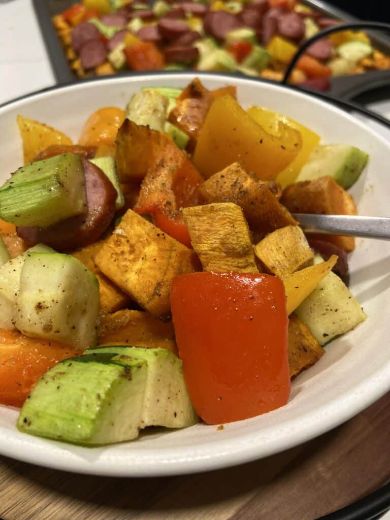 Close up photo of baked zucchinis, andouille sausage, and bell peppers