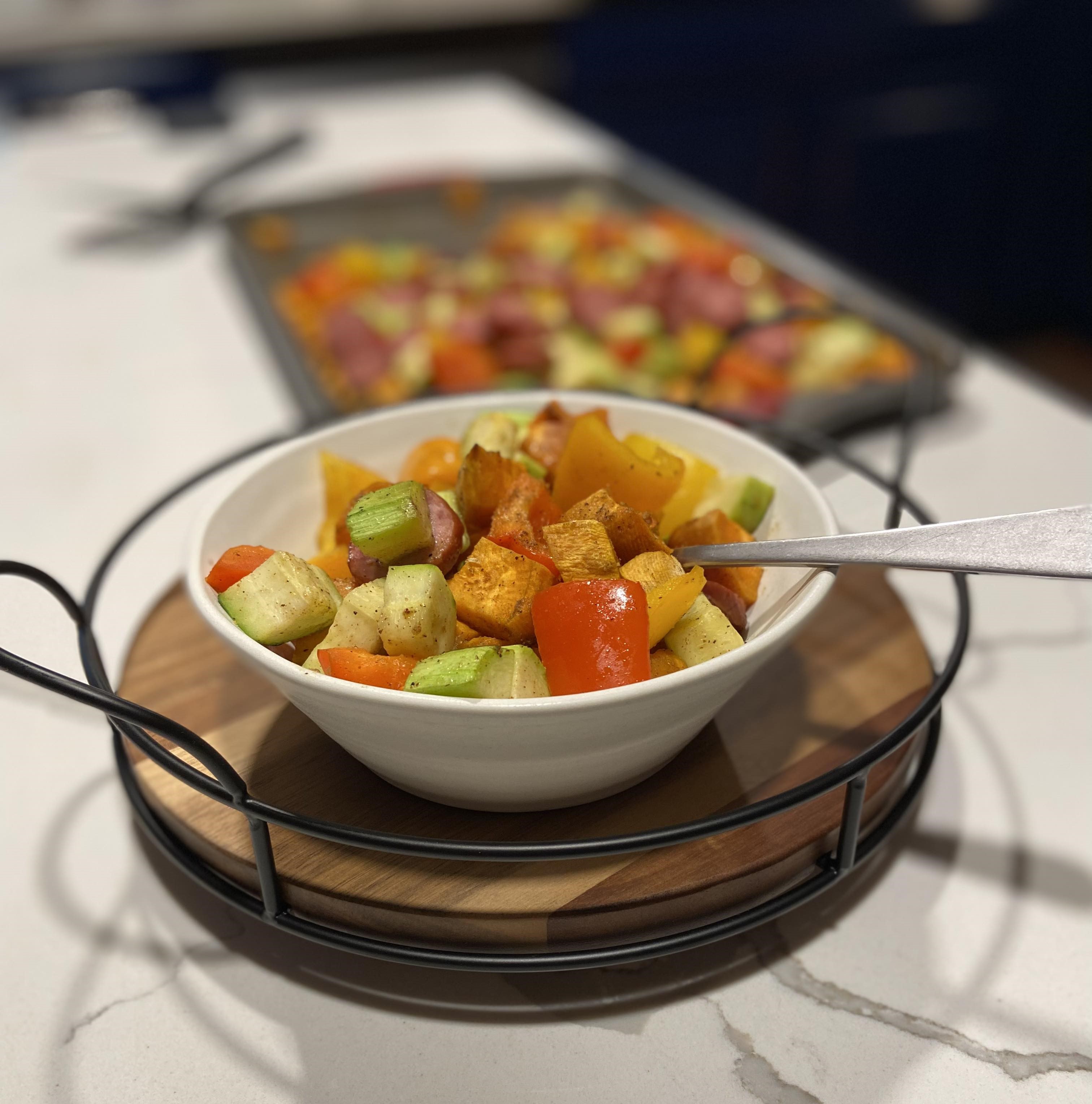 Photo of andouille sausage, peppers, and sweet potato sheet pan dinner. savory dinner bowl featuring andouille sausage paired with colorful sautéed bell peppers, zucchini, sweet potato's creating a delicious and visually appealing meal.