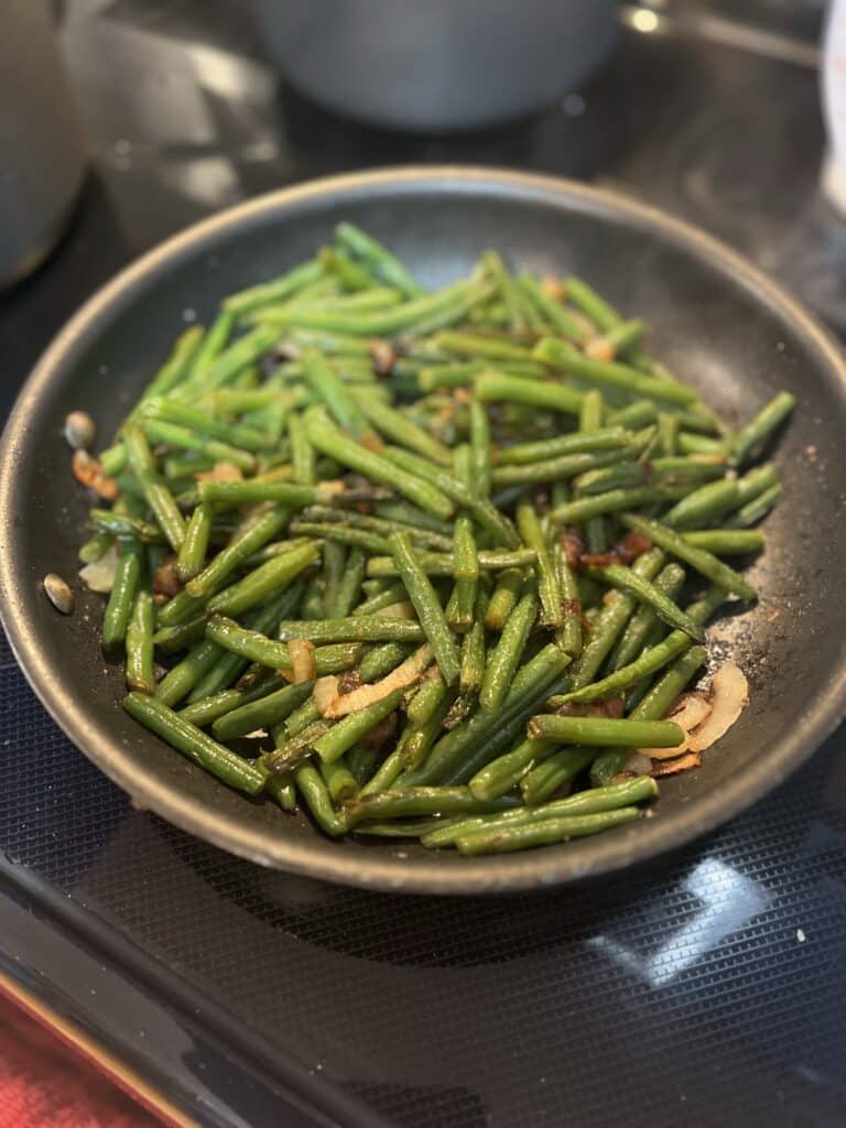 sauteed onions with fresh cooked green beans in a skillet pan