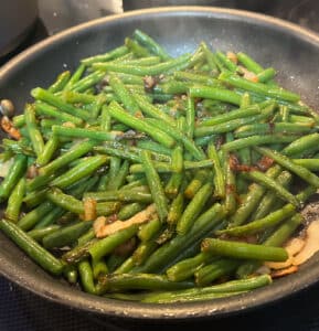 skillet green beans in a skillet with onion and garlic