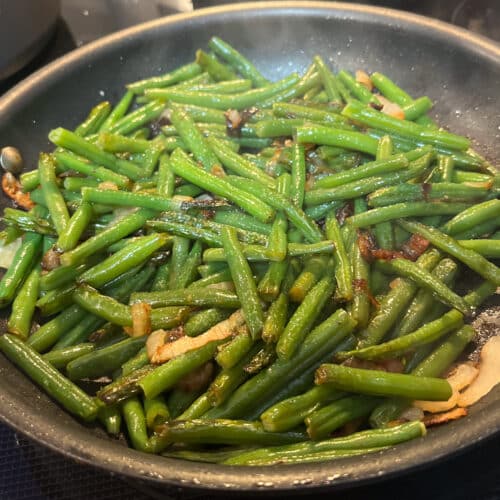 skillet green beans in a skillet with onion and garlic