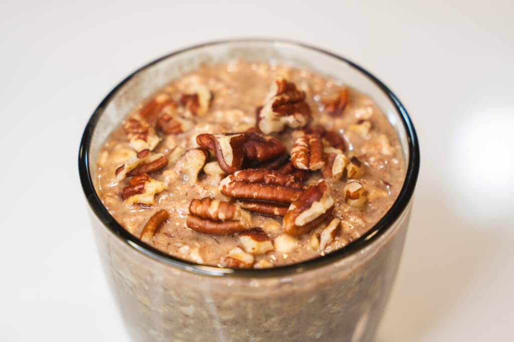 banana bread overnight oats in a glass jar and pecans on top