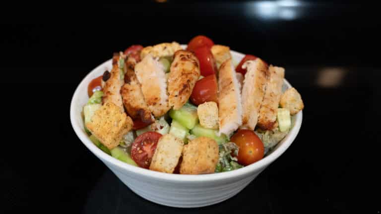 rotisserie chicken caesar salad in a white stone wash bowl