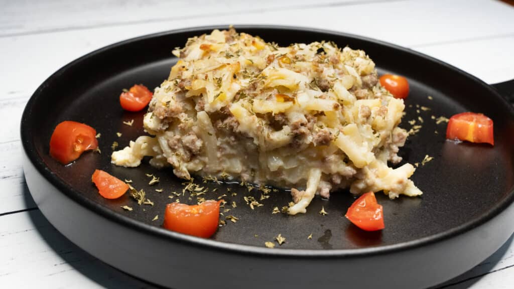 Breakfast Casserole on a black plate with tomatoes and parsley