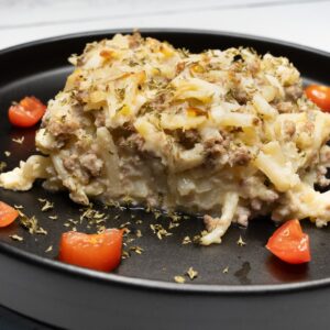 Breakfast Casserole on a black plate with tomatoes and parsley