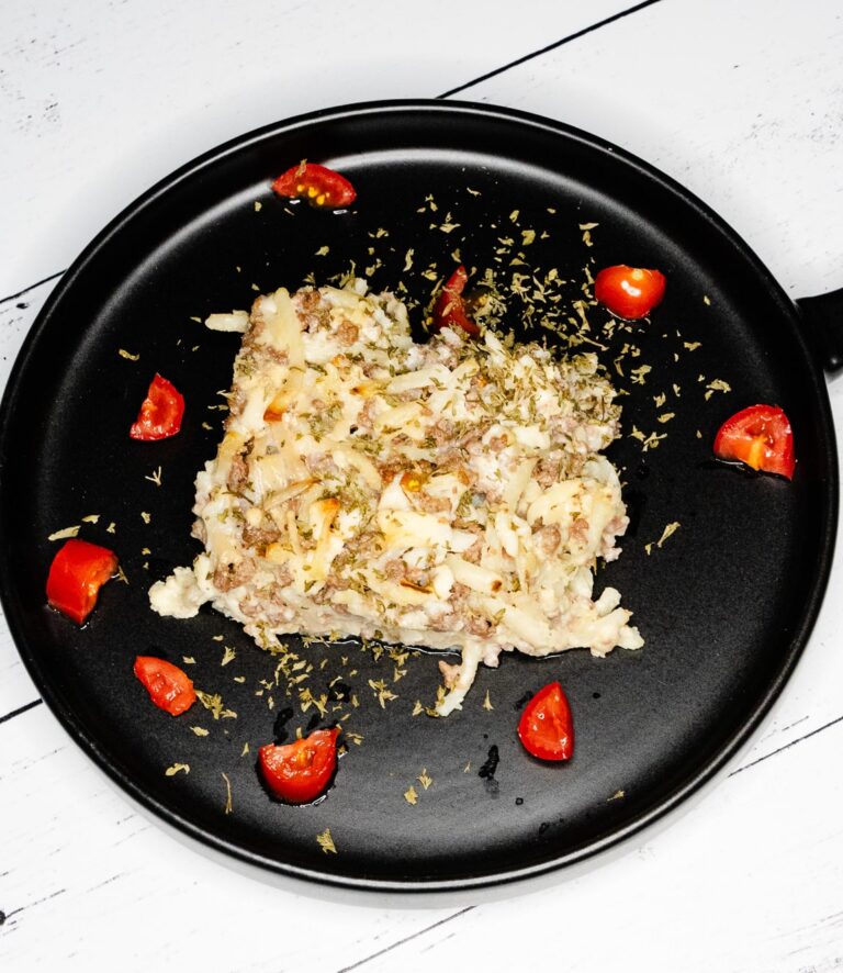 Breakfast Casserole on a black plate with tomatoes and parsley