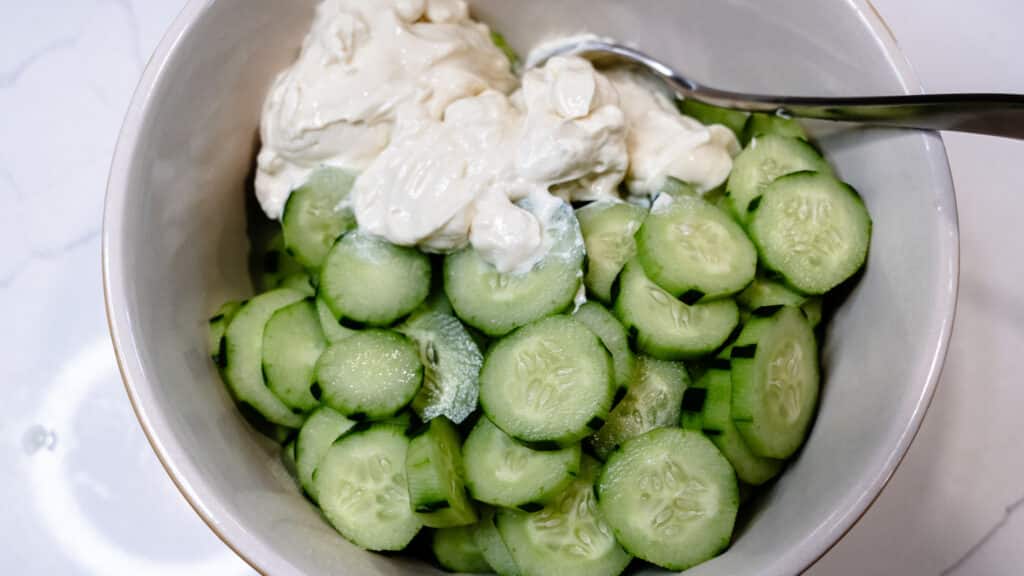 Mom's Fresh Cucumber Salad with cucumbers sliced and mayo ready to stir in a white bowl