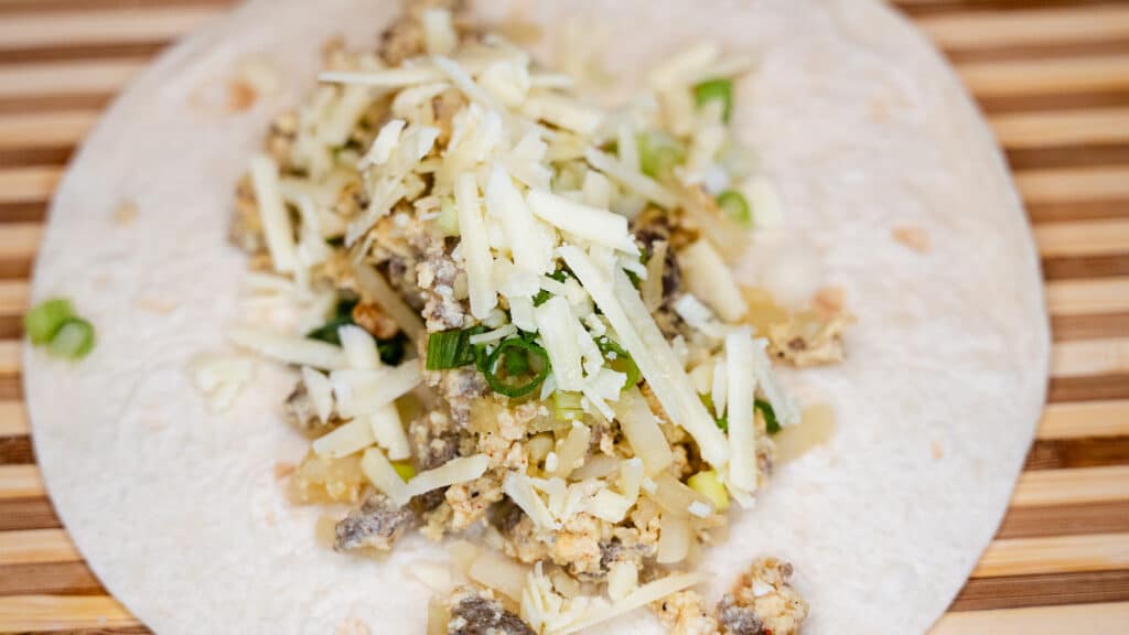 Breakfast burritos with shredded cheese, onions, and sausage