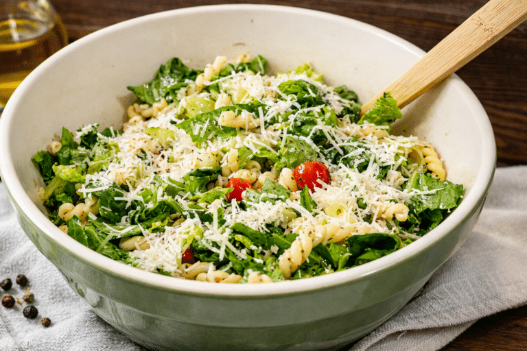 Italian lettuce pasta salad in a bowl with a wooden spoon