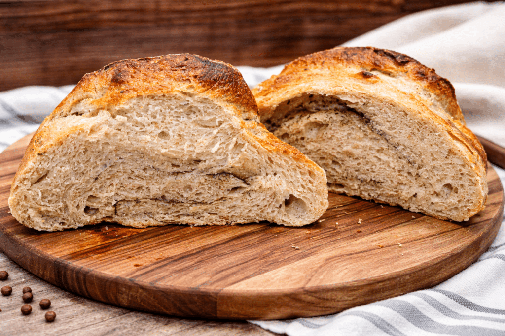 garlic herb artisan sourdough bread loaf cut in half sitting on a cutting board