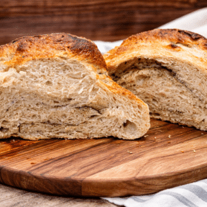 garlic herb artisan sourdough bread loaf cut in half sitting on a cutting board