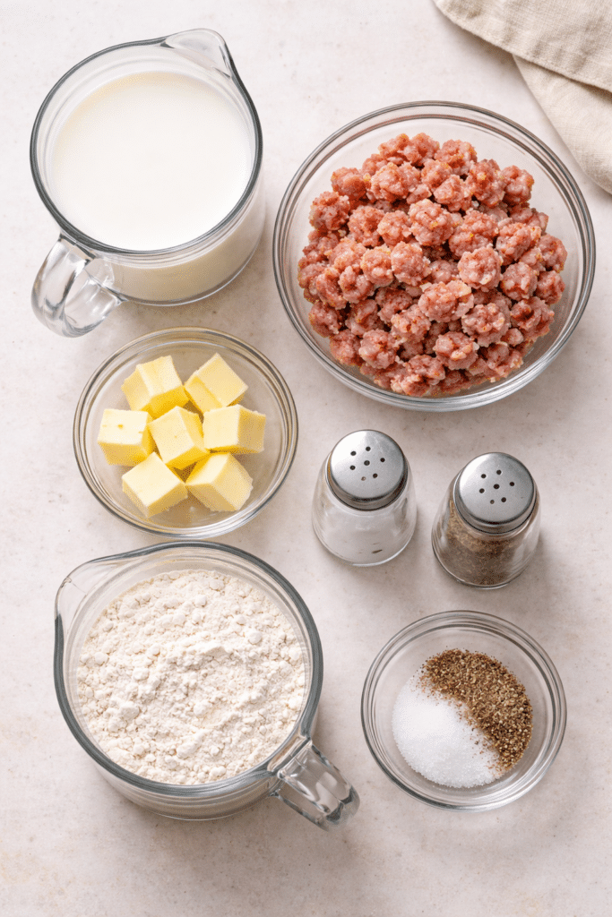 ingredients for homemade sausage gravy laid out on the counter in separate glass containers
