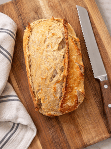 a rustic classic artisan sourdough loaf sitting on a cutting board, showing an above overhead shot.