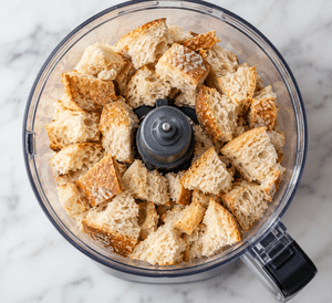 artisan sourdough bread chunks sitting in the food processor ready to be grinded