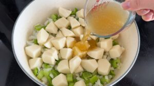 Adding diced red potatoes and chicken broth to the Dutch oven for creamy corn chowder