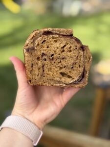 Hand holding a slice of pumpkin cinnamon swirl sourdough showing the swirl in the crumb