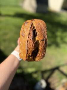 Close-up of the golden scored crust of a pumpkin cinnamon swirl sourdough loaf with the swirl peeking through